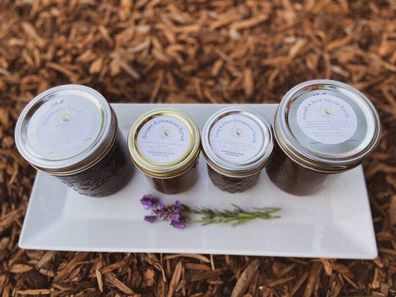 herbal syrups on a white platter with a lavender flower