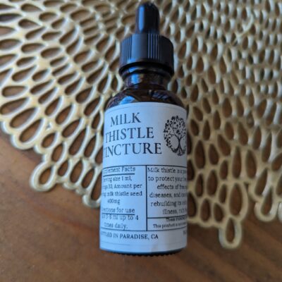 Milk Thistle tincture on gold and wood counter